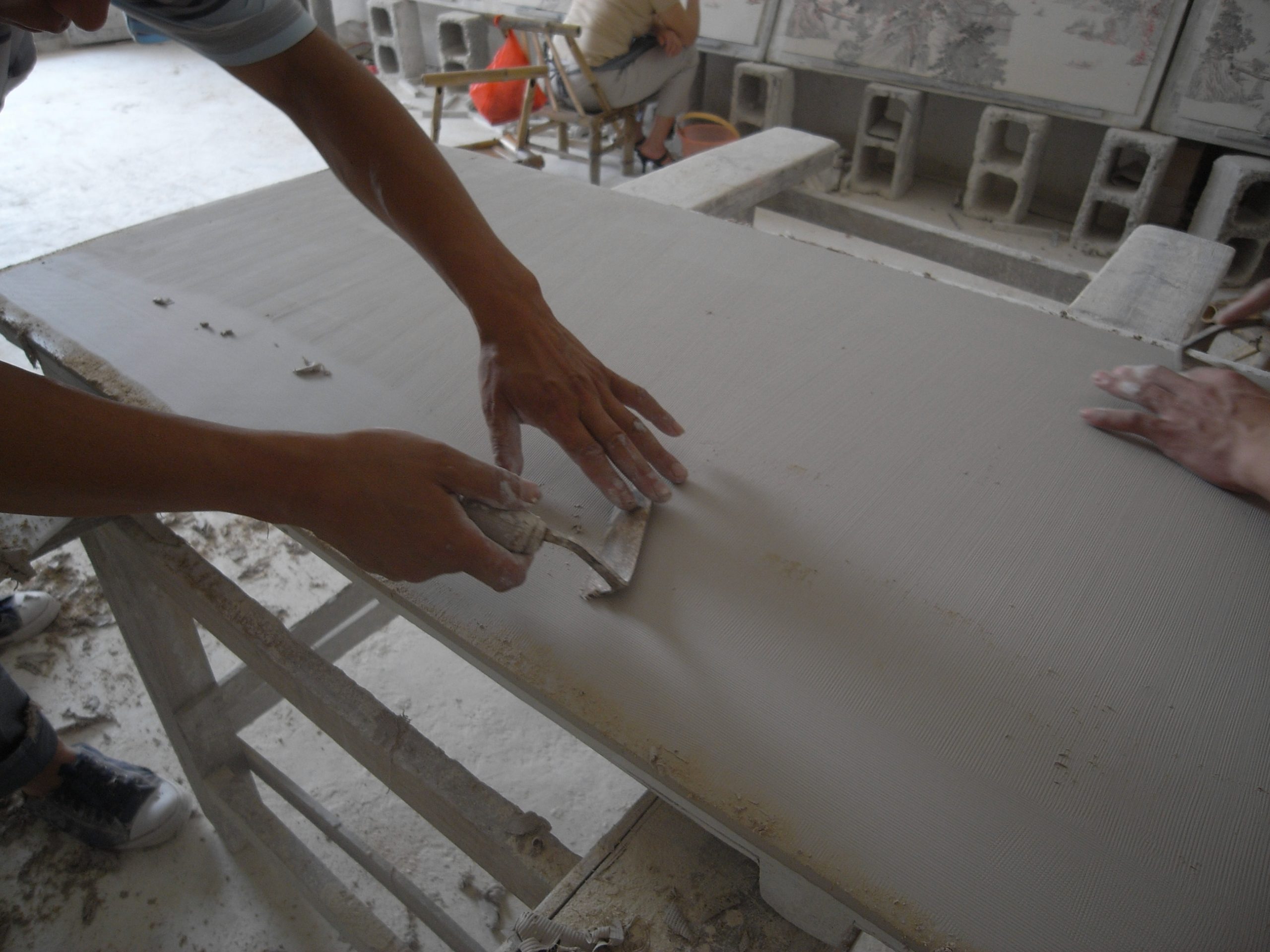 A studio assistant smoothing out the clay surface of a work. Photo courtesy of the artist.